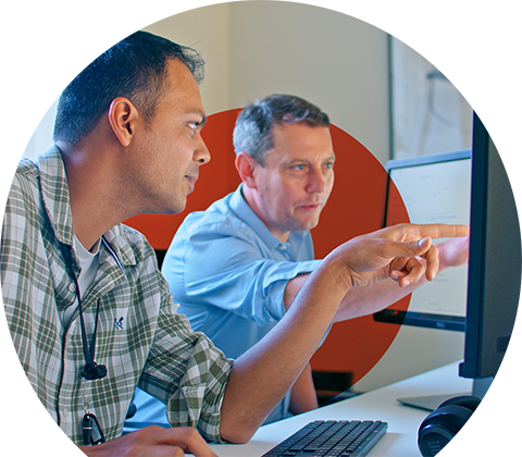 Zeeshan and David pointing at a monitor