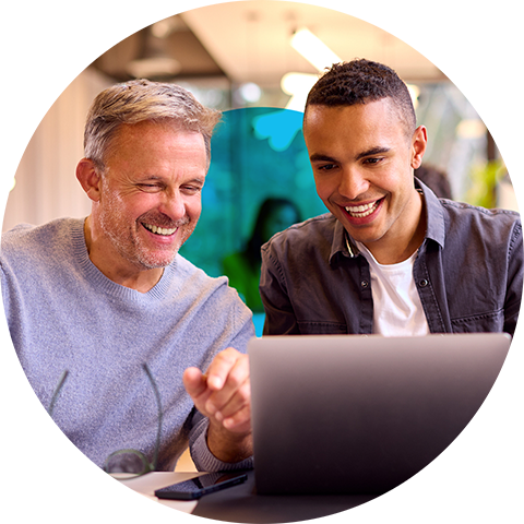 two people laughing at a laptop