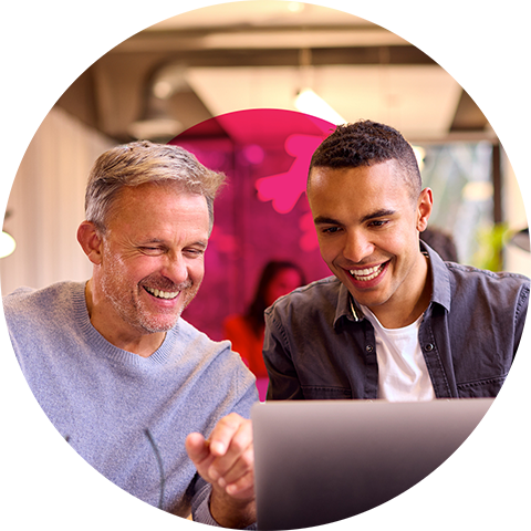 two people laughing at a laptop